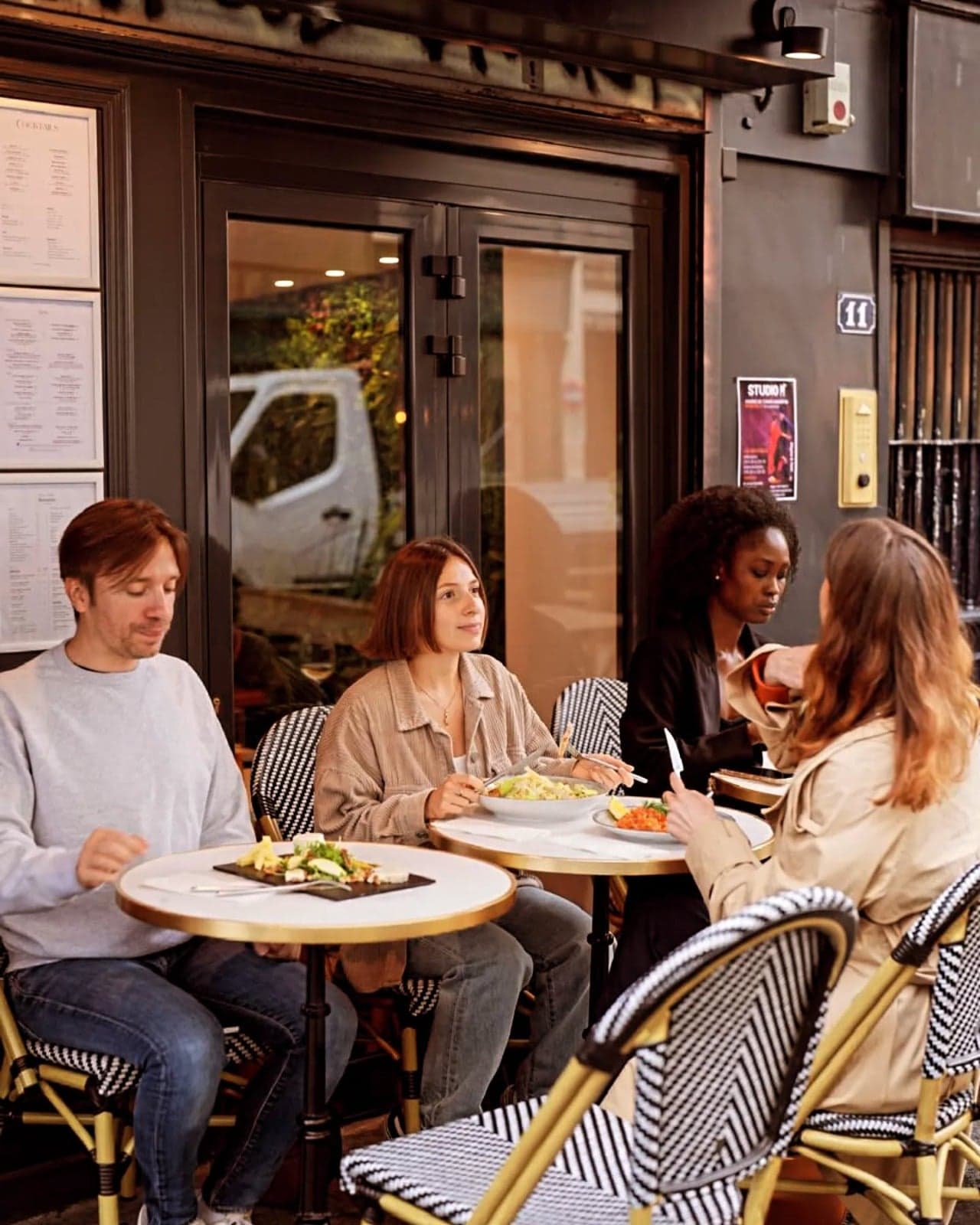 Quatre amis attablés à la terrasse de Chez Sophie, sur des chaises en rotin